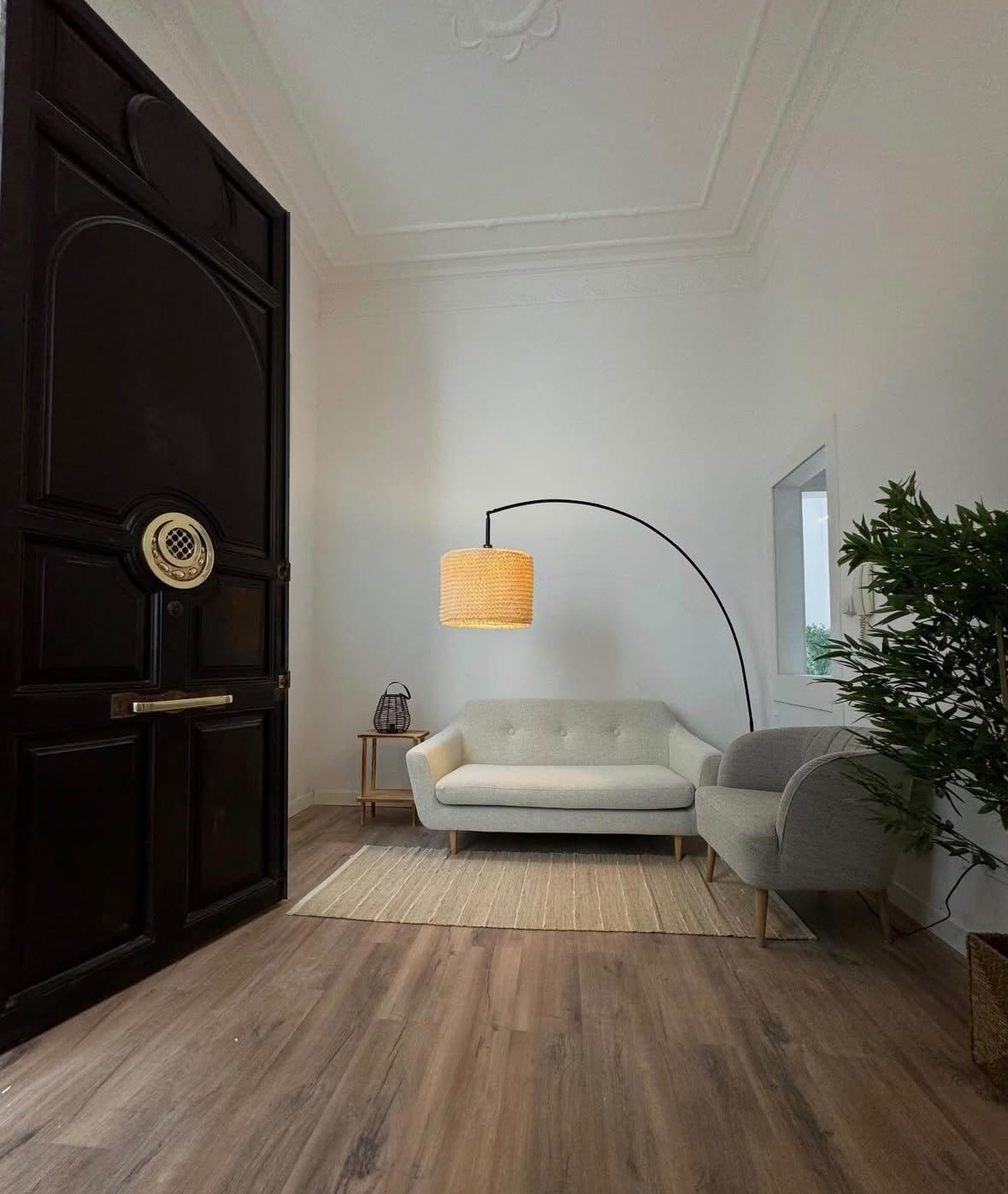 Salón de espera reformado con sofá, butaca, lámpara de arco y puerta de época